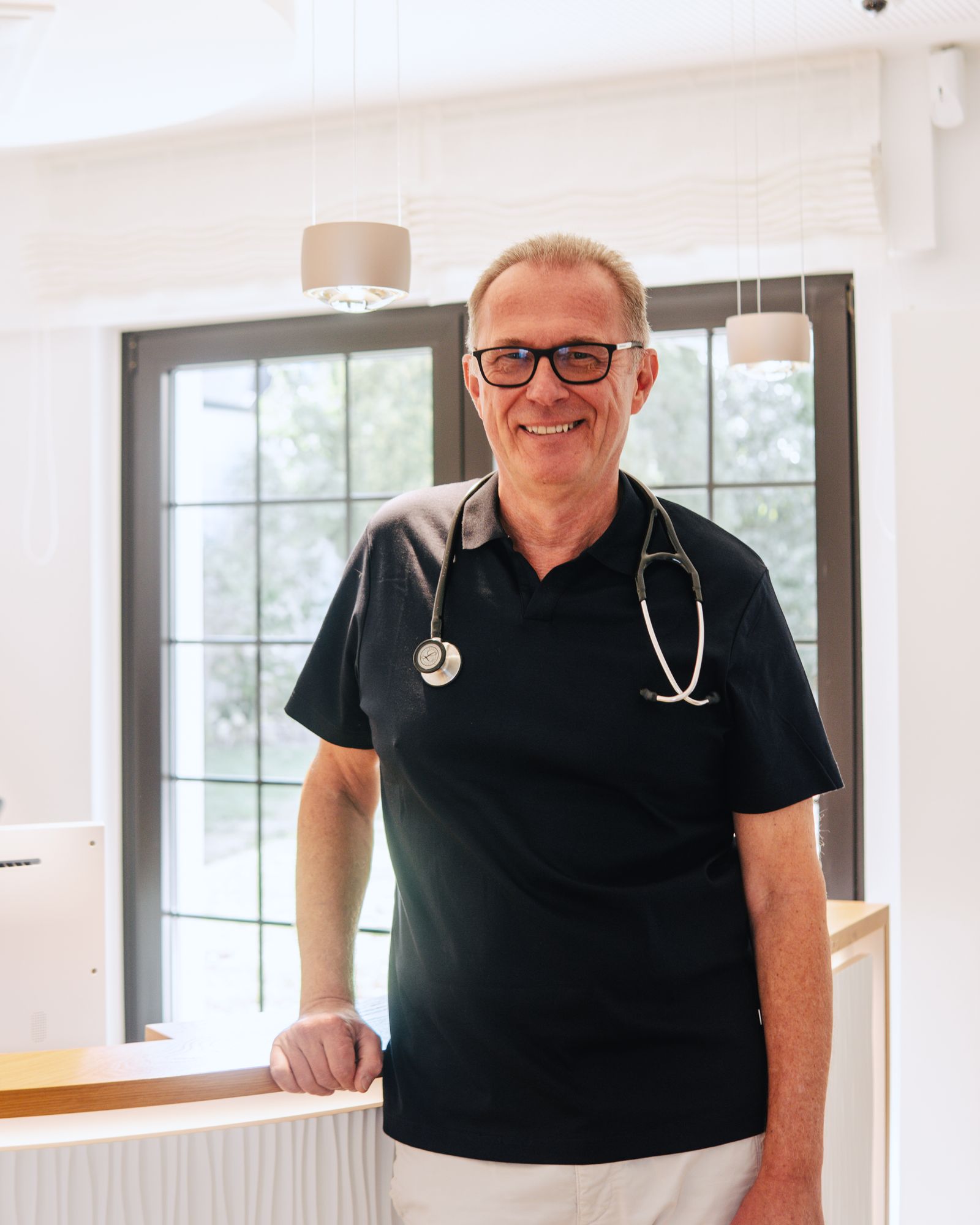 Dr. Stefan Balzer lächelnd am Empfang seiner Praxis
